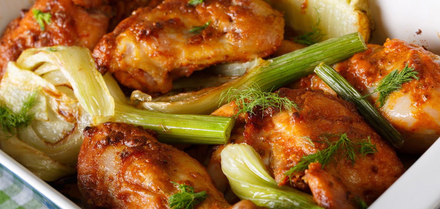 Golden brown roast chicken with caramelized fennel bulbs.